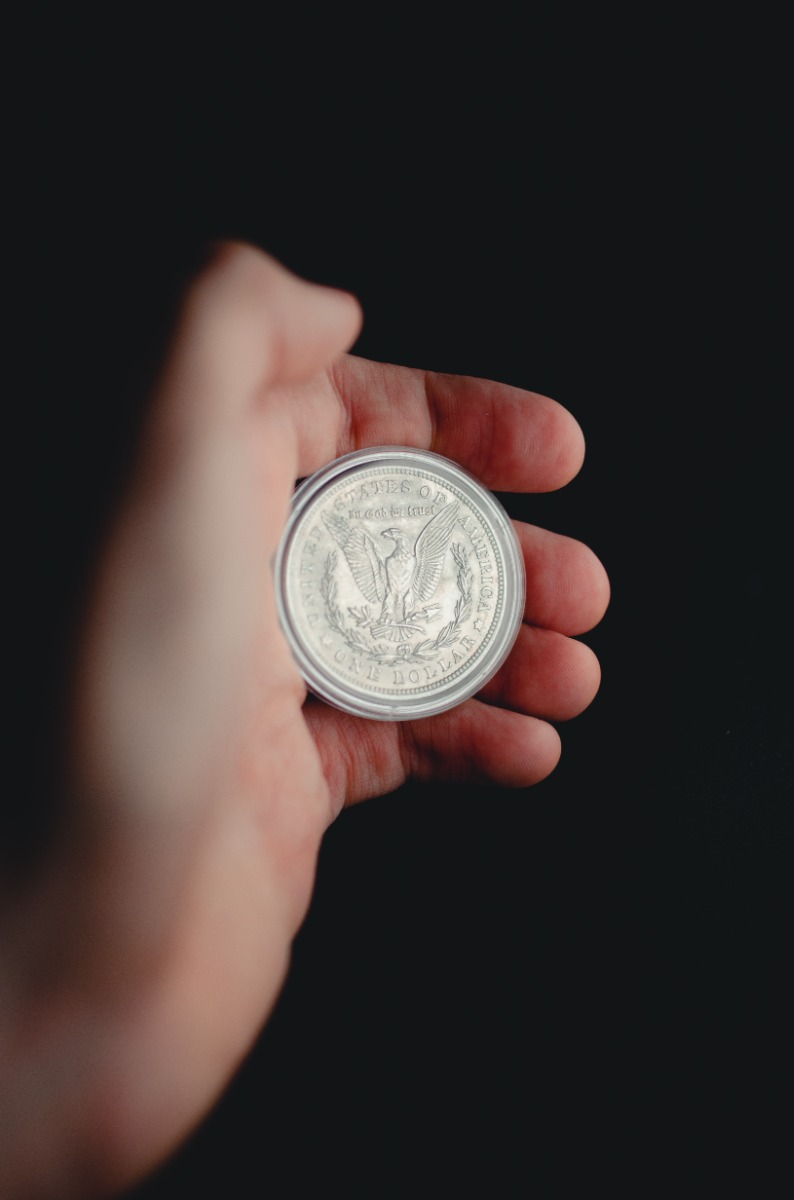 hand holding a Morgan silver dollar against a black backdrop