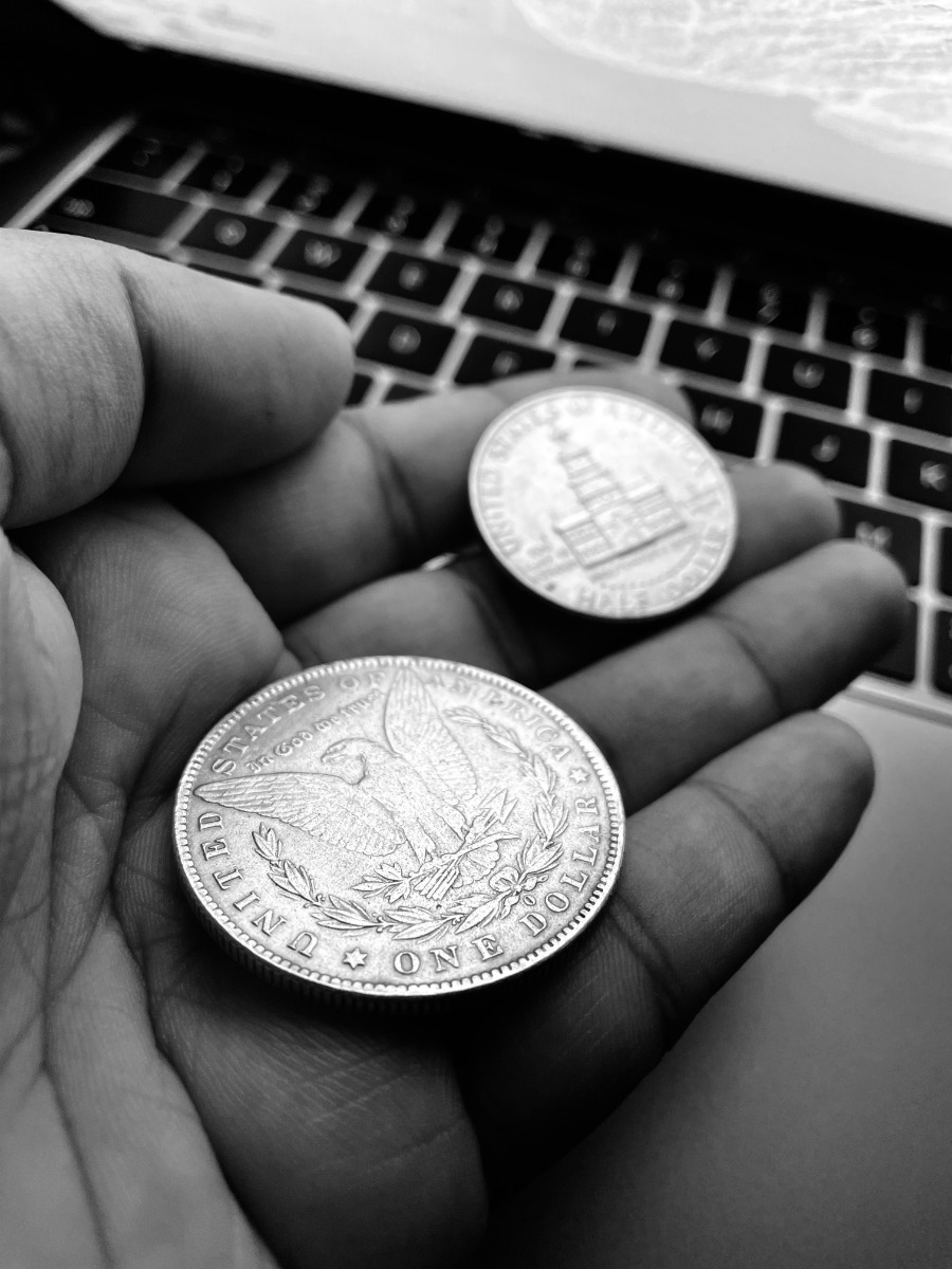 a person holding two silver US coins.
